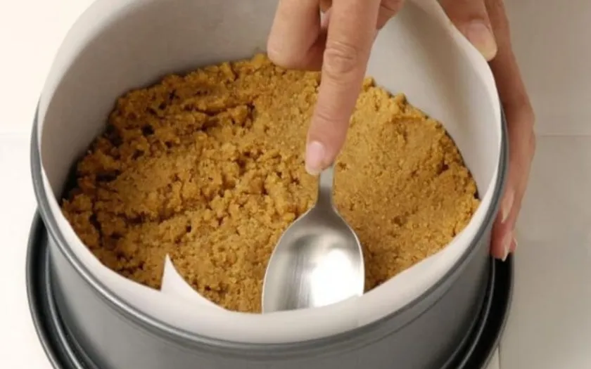 Nén chặt hỗn hợp bơ và bánh quy để định hình phần đế bánh mousse