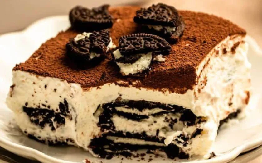 Tiramisu Oreo với lớp kem trắng mịn xen kẽ vụn bánh Oreo đen giòn, phủ thêm bánh quy nghiền trên mặt.