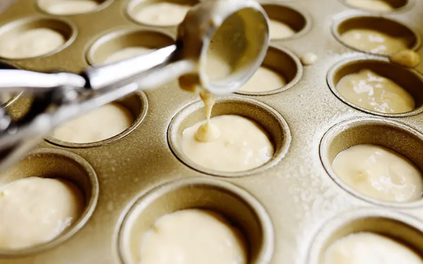 Dùng muỗng hoặc dụng cụ múc bột, múc bột vào từng ô, đổ đầy khoảng 2/3 khuôn để chừa chỗ cho bánh nở