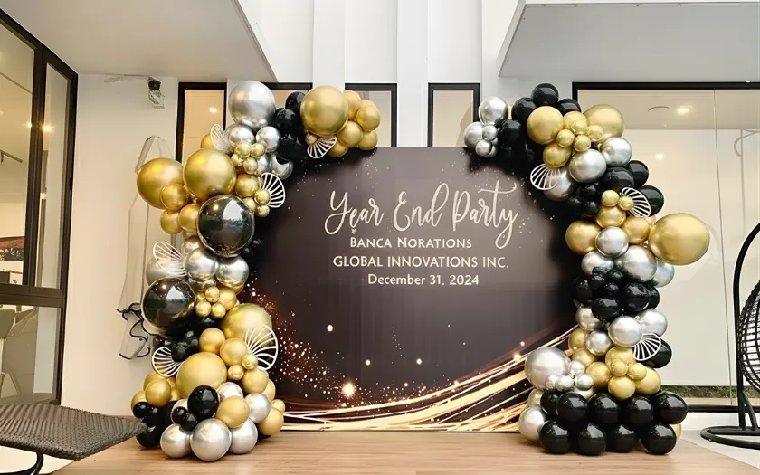 Phông nền đen ánh kim và dải bong bóng màu vàng, bạc tạo nên một không gian sang trọng cho buổi tiệc.