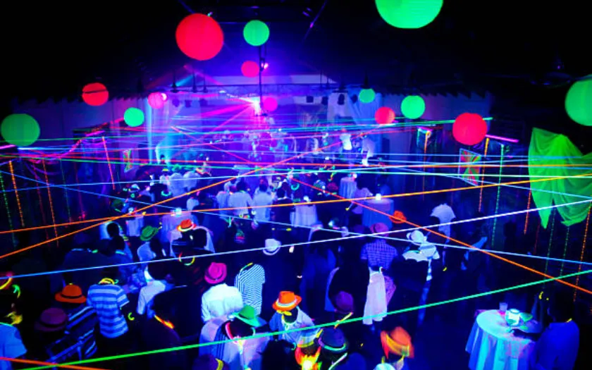 Không gian tiệc rực rỡ với ánh sáng neon và màu dạ quang, tạo không khí năng động, trẻ trung